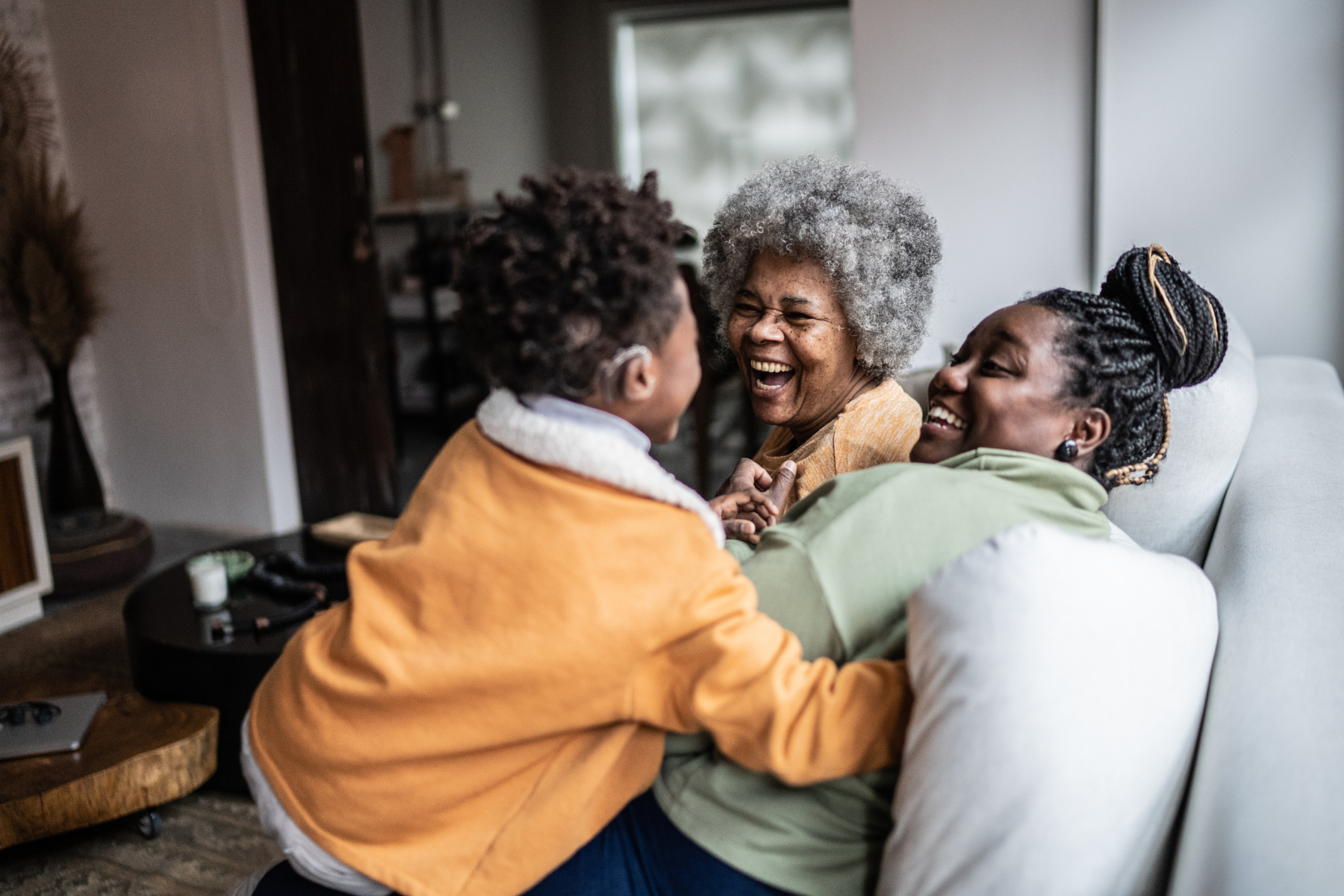 Deaf child playing with his mother and grandmother in the living room at home