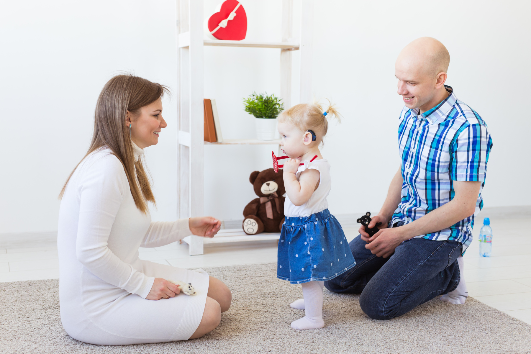 Hearing aid in baby girl's ear. Toddler child wearing a hearing aid at home.