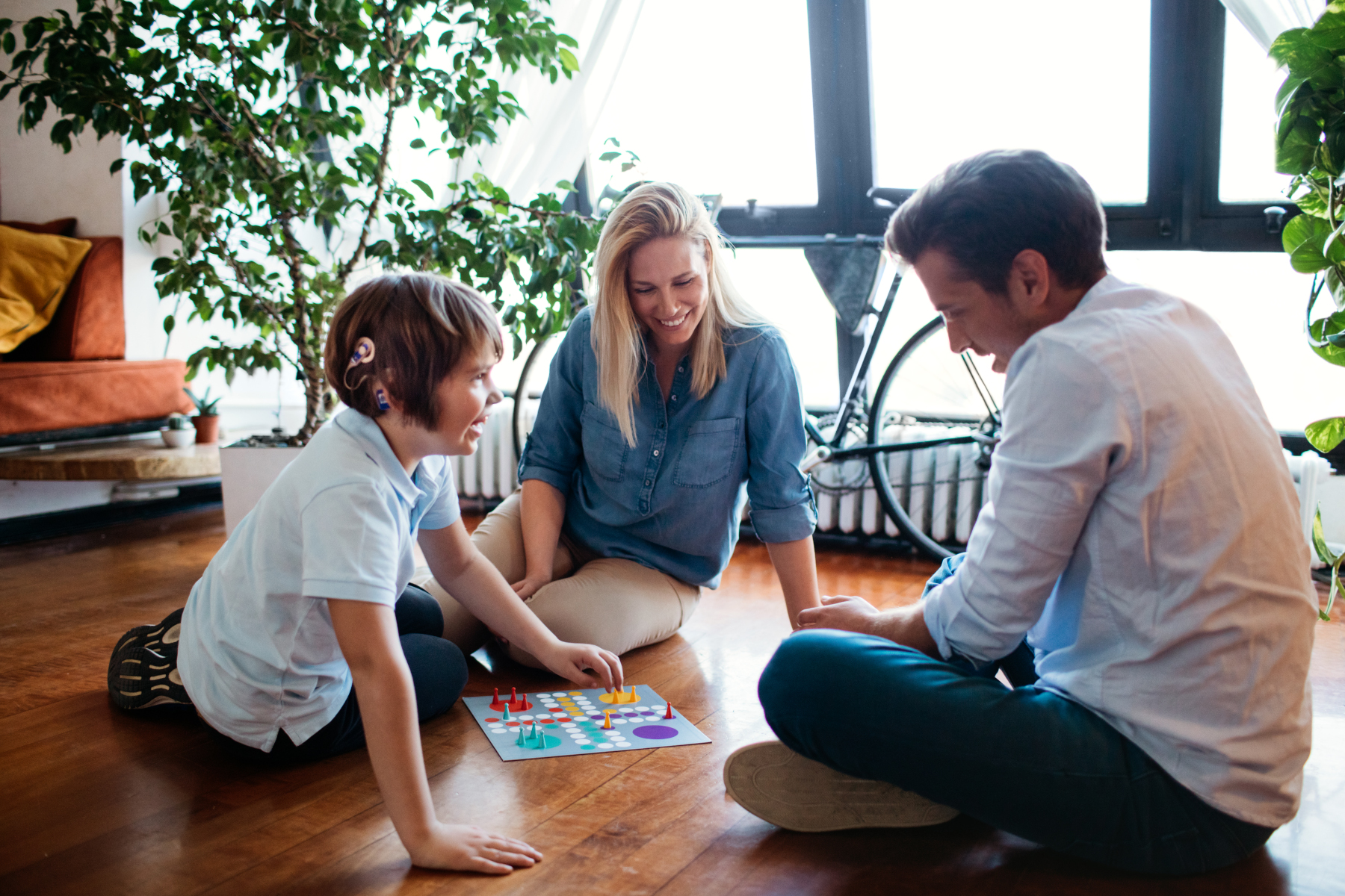 child with cochlear implant playing board game with parents