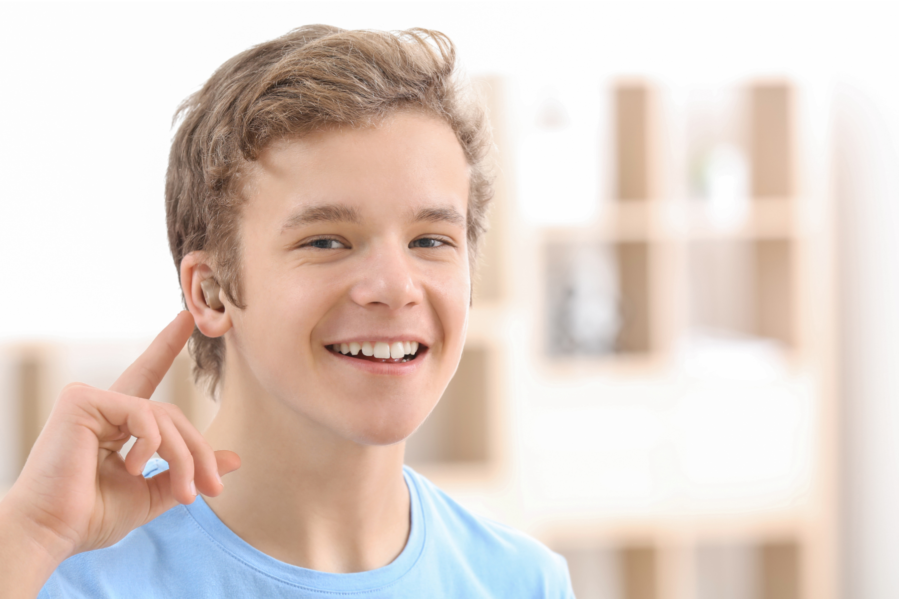 teenage boy with an earing aid, pointing to his ear