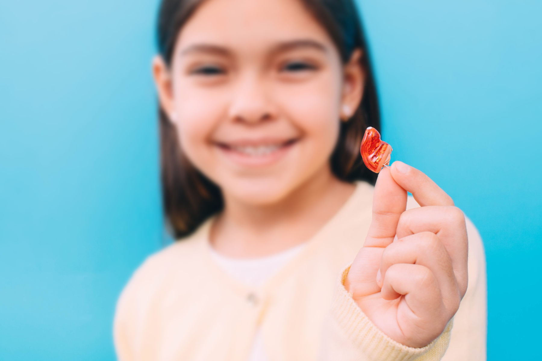 young latina girl showing her hearing aid