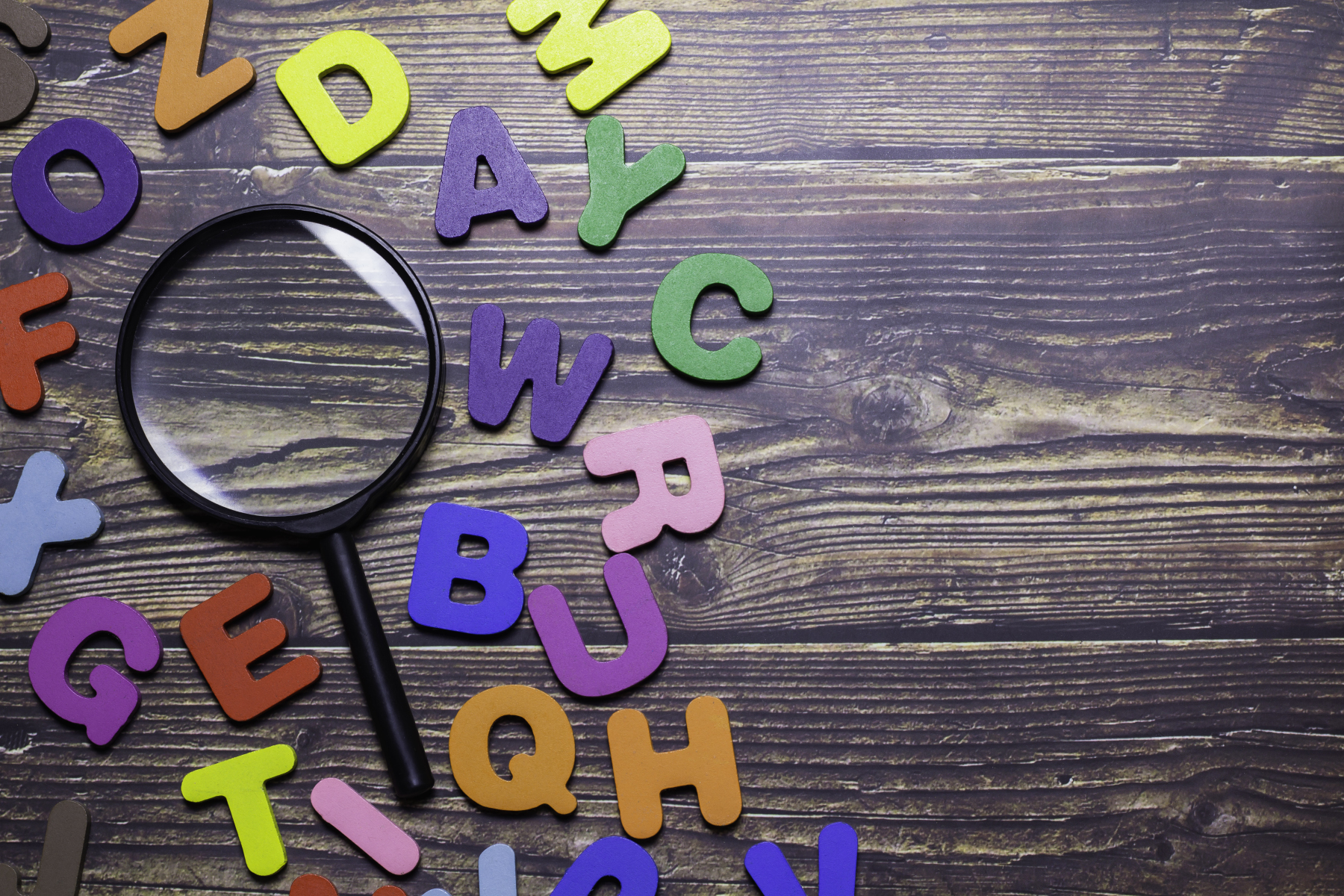 magnifying glass in the middle of colored letters