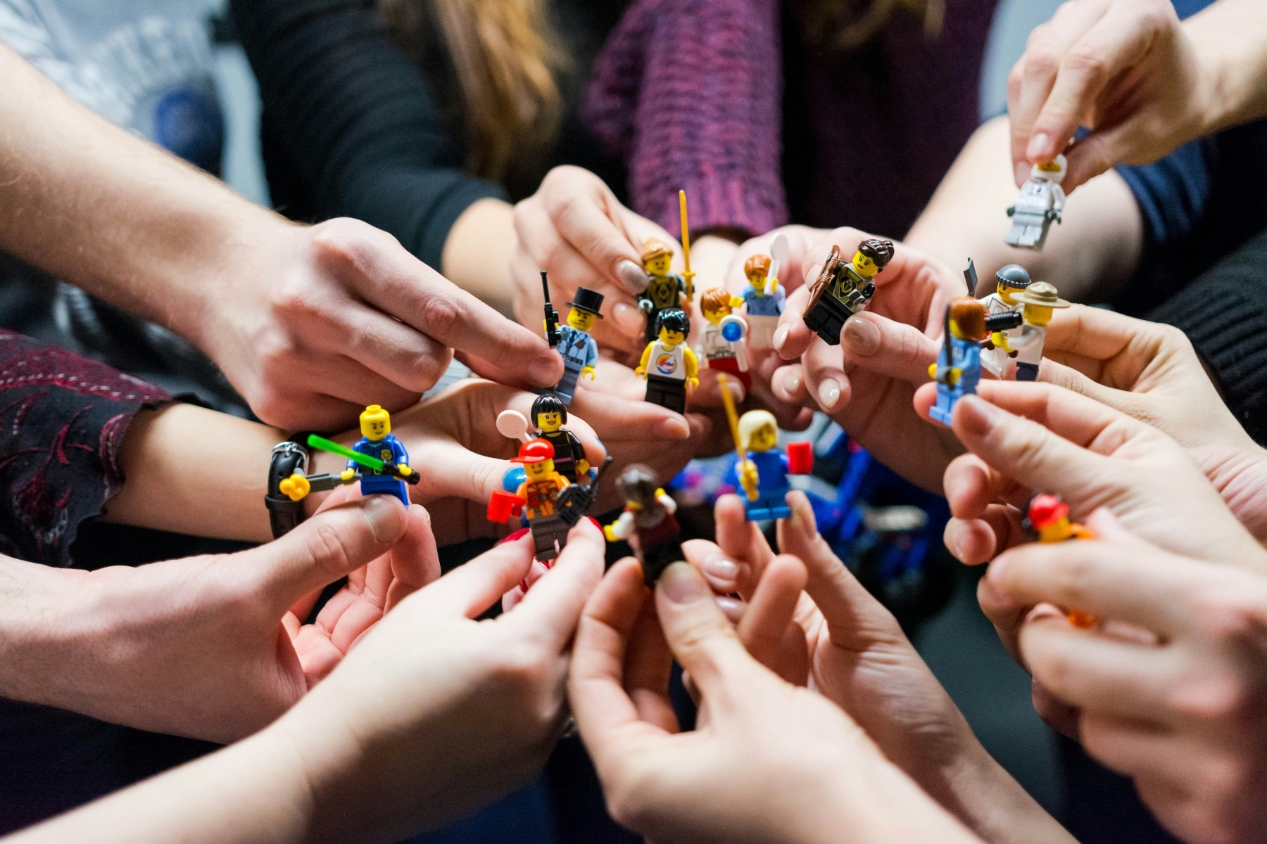 people holding lego figurines all together